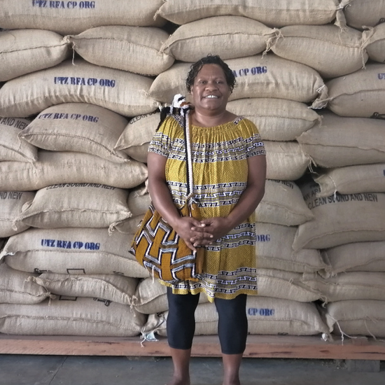 Moanti Ise standing infront of hessian bags filled with coffee